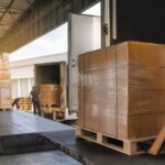 Khu giao nhận hàng hóa nội địa với pallet và xe tải không thương hiệu. Ảnh minh họa tin tức.